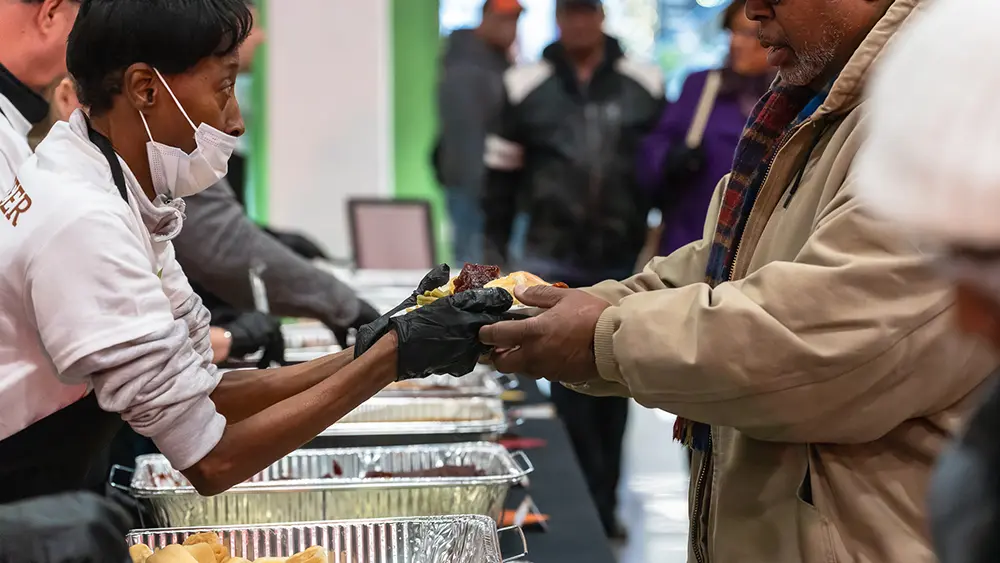 Feast of Giving volunteer handing food to diner